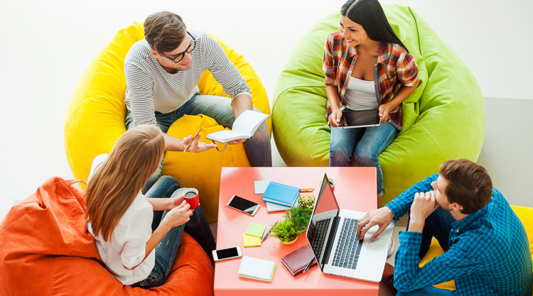 Group of co-workers siting on colorful beanbags, collaborating on work