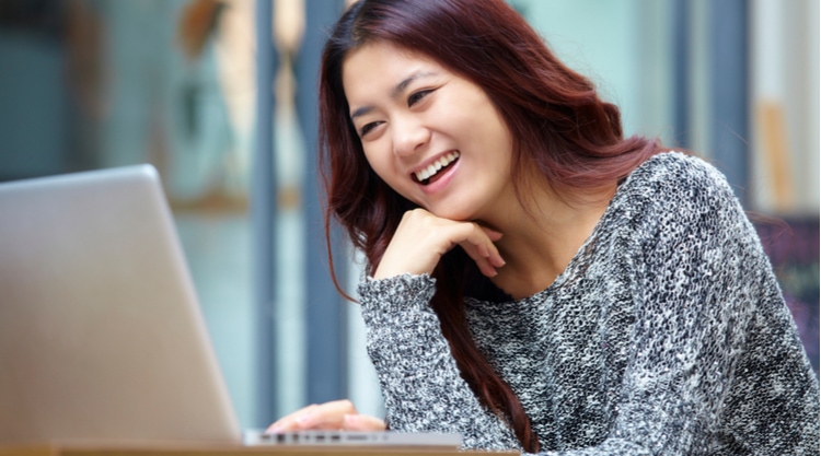 A woman smiling while working on her laptop