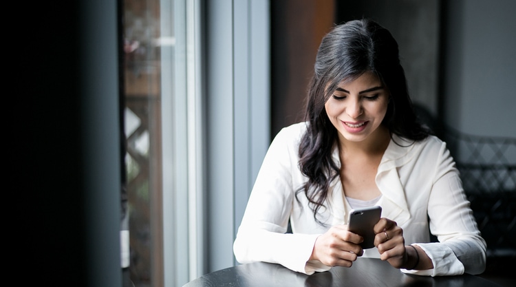 A woman looking down at her cell phone sitting in a cafe