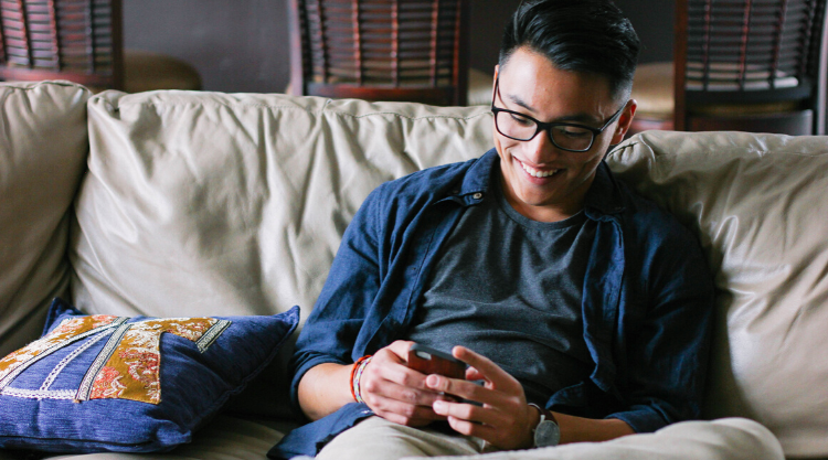 A man looking at his cell phone while sitting on the couch