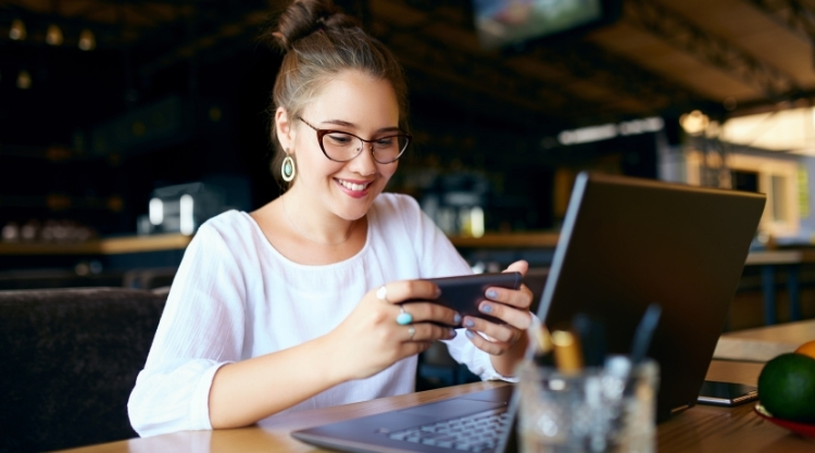 A woman holding a cellphone while working in a restaurant