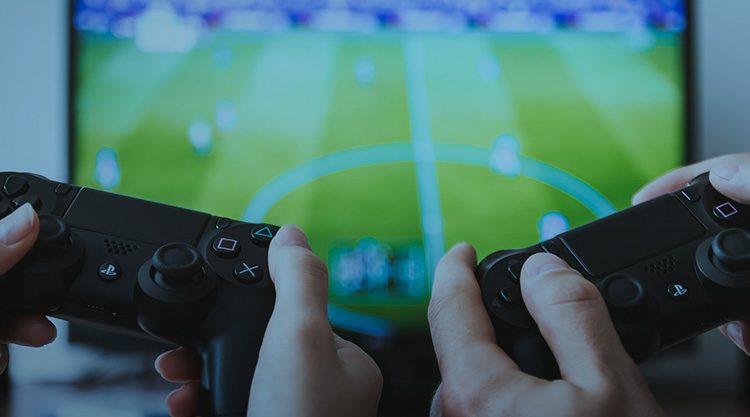 Two hands each holding game controllers with a tv screen in front of them