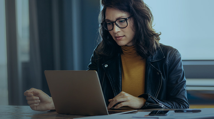 An adult woman working on a laptop in an office space