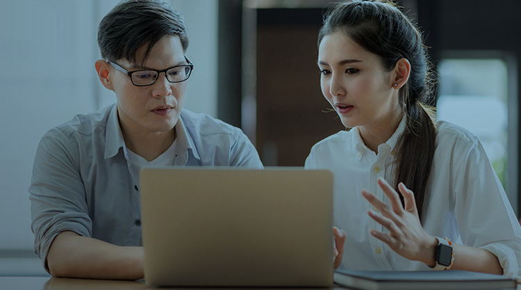 Adult man using his laptop and a young woman next to him looking