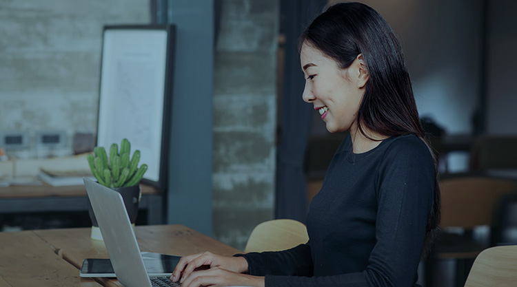 Smiling young woman typing on her laptop in an office space