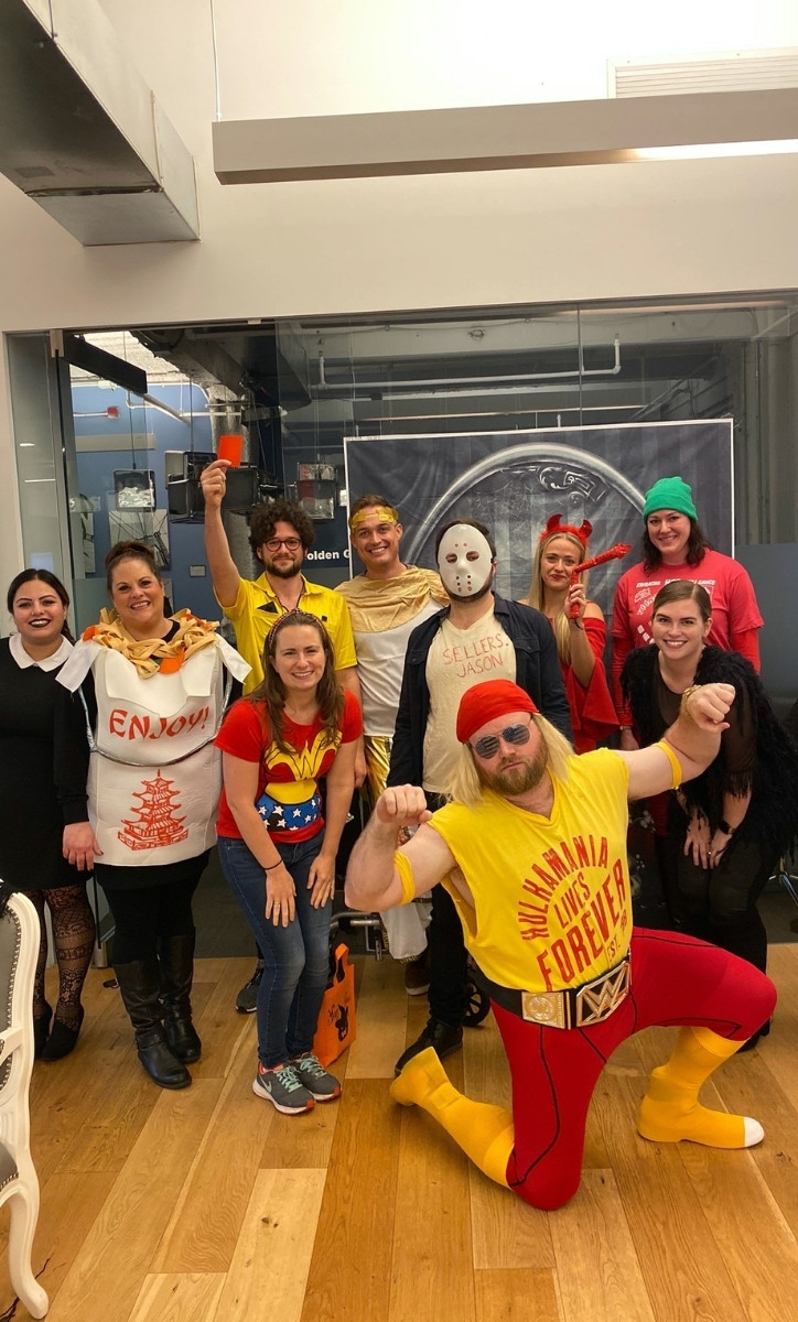Ten smiling PubMatic employees wearing Halloween costumes in an office