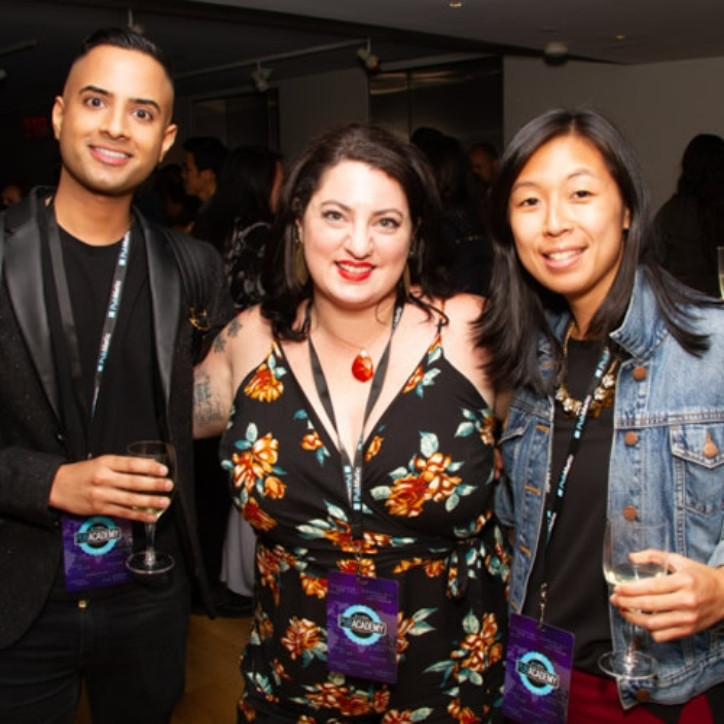 Three smiling adults wearing PubMatic lanyards. Two of the adults are holding wine glasses