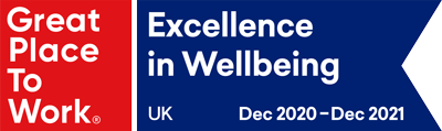 Red square with white text "Great Place To Work". A blue pentagon to its right with white text "Excellence in Wellbeing UK Dec 2020-Dec 2021"