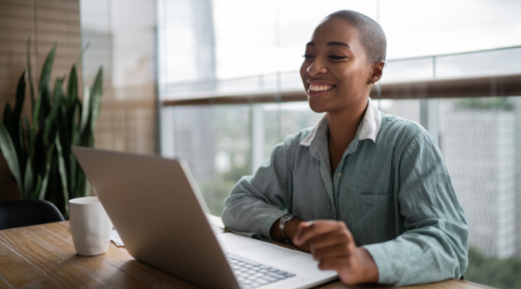 Young black woman smiling while looking at laptop