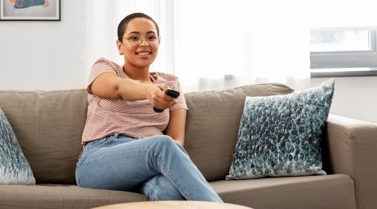 Happy african american woman watching tv at home