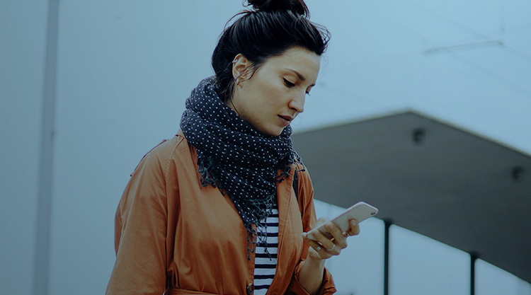 Adult woman wearing a scarf looking down at her cell phone in hand