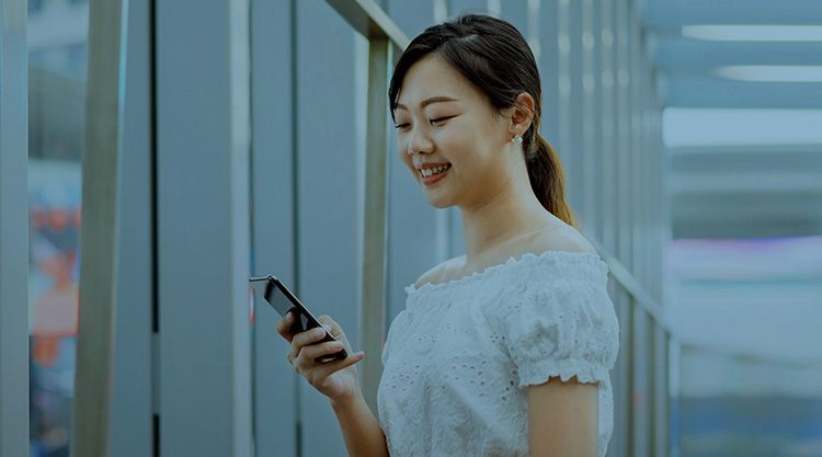 Smiling adult woman looking at cell phone standing inside a building