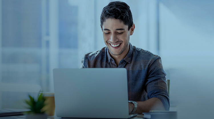 Smiling adult man working on laptop while in an office space