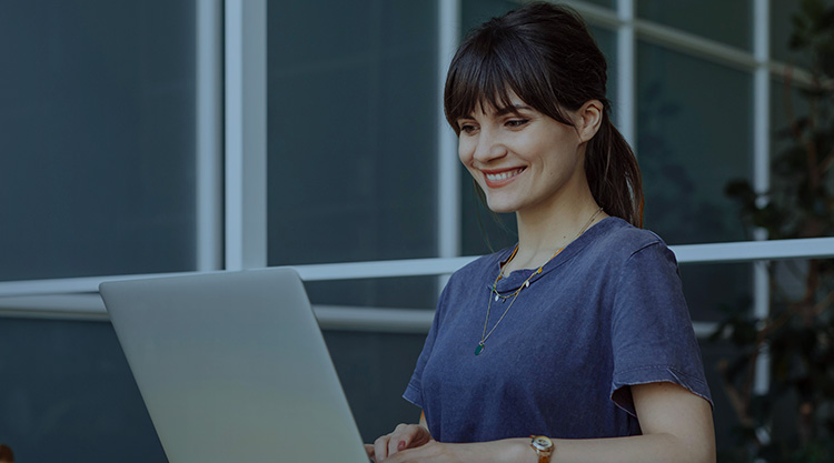 Adult woman smiling and looking at her laptop