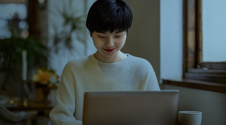 Smiling young woman in a café looking down at her laptop