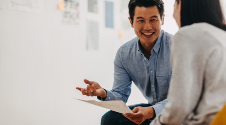 Asian man smiling while discussing work with colleague