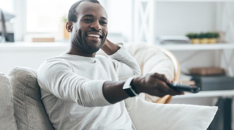 Smiling Black man watching TV at home