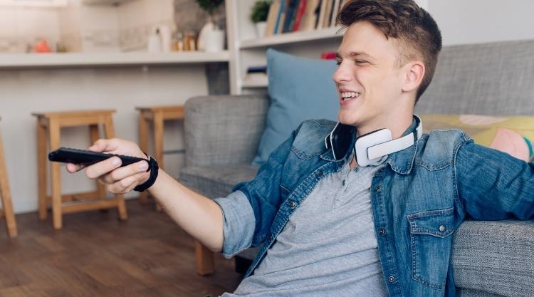 Young man holding a TV remote while smiling