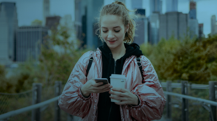 Smiling Young Woman holding a smartphone & coffee