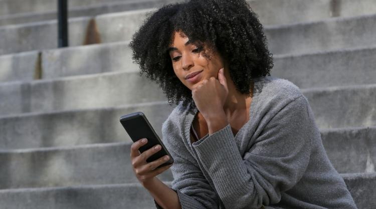 Woman sitting on stairs looking at phone.