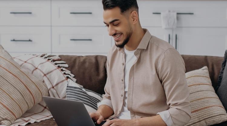 Positive handsome Indian man, working from home smiling