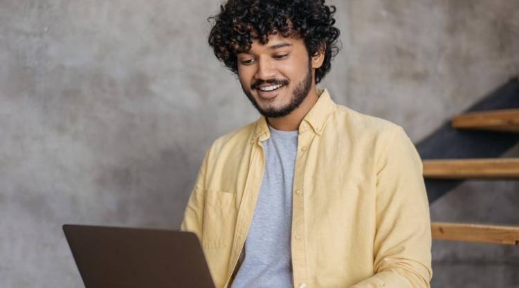 Young man with yellow button-down shirt on laptop