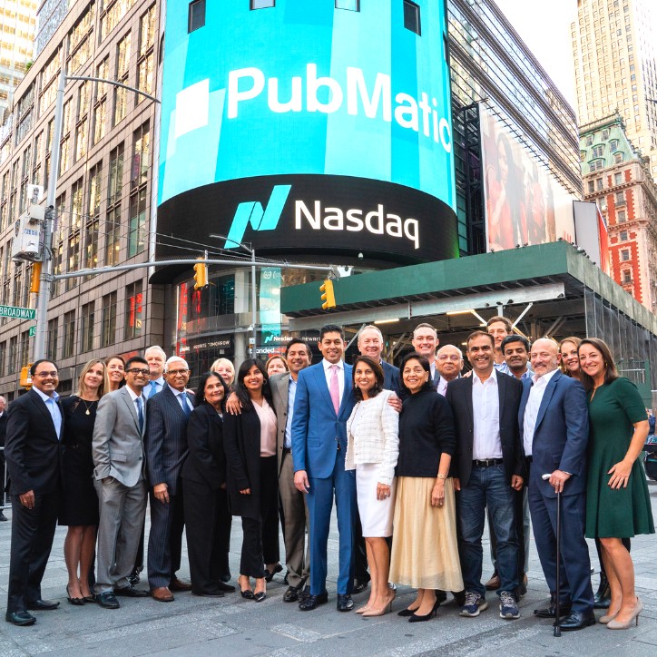 Twenty-three smiling Pubmatic employees stand in front of Nasdaq bell celebrating