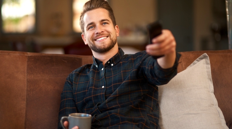 Smiling young man enthusiastically using his remote control