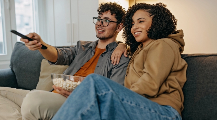 A young couple is very happy as they watch television together