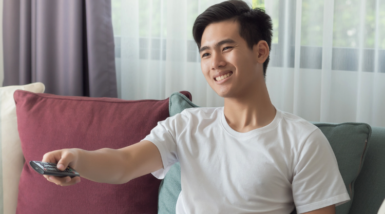 A smiling young man operates his television