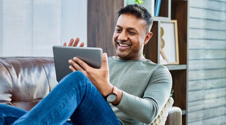 A happy man uses his device on the couch