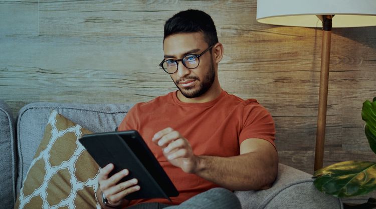 Man in red shirt wearing glasses looking at tablet
