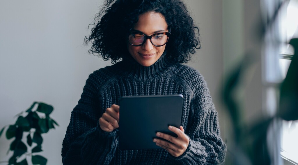 Young business woman with eyeglasses working on her digital tablet while standing in the living room