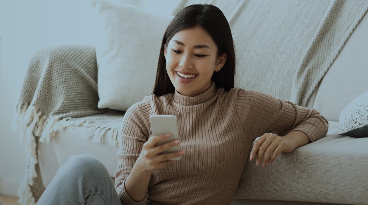 Happy Asian Girl Messaging on Phone at Home