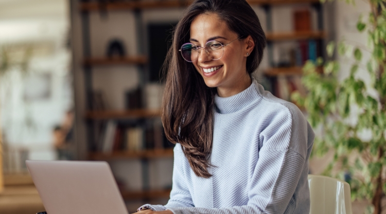 A smiling young woman uses her laptop