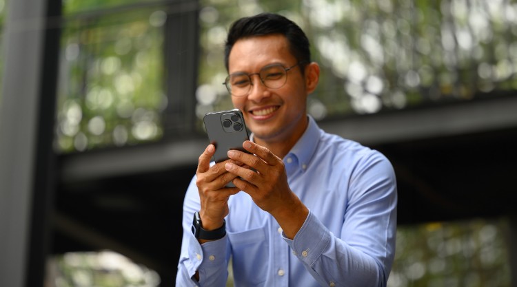 A smiling man uses his mobile device