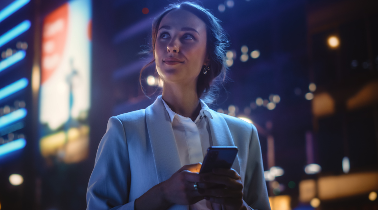 A smirking woman mischievously looks to the sky while using her mobile device