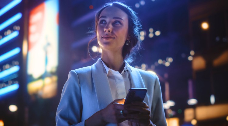 A young woman pauses from her mobile device to consider the world around her