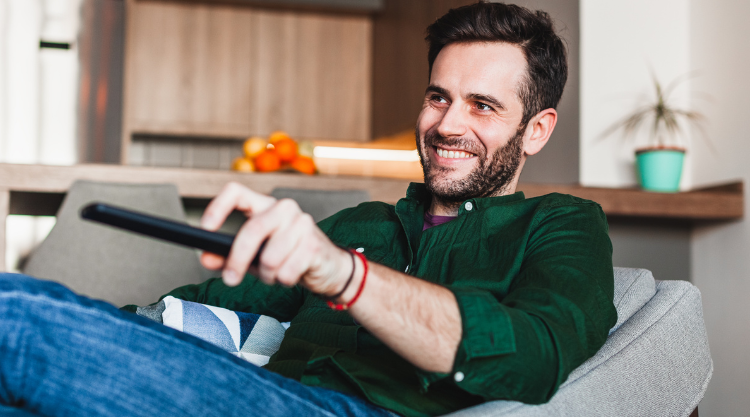 Young man holding remote controller watching tv