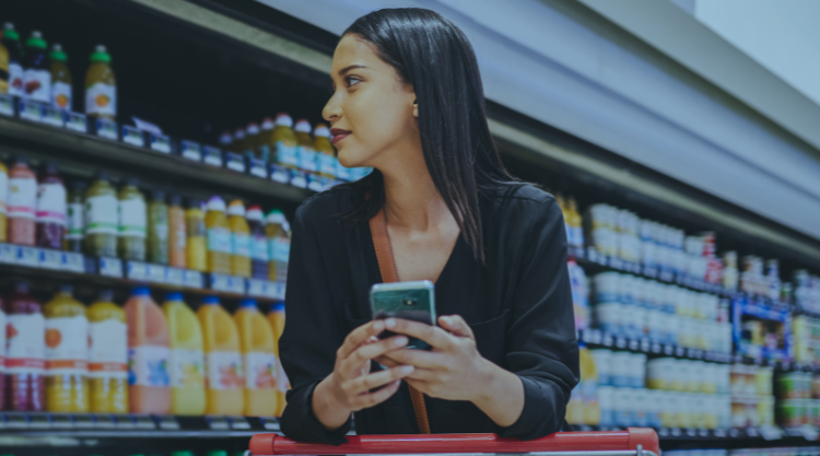 Shot of a young woman using a smartphone while shopping in a grocery store