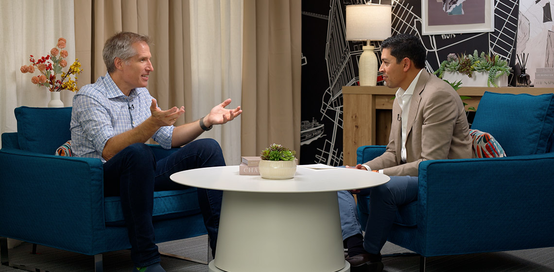 An interview screenshot featuring Rajeev Goel and Brian O'Kelley