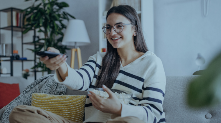 Young woman in sweater enthusiastically uses her remote control